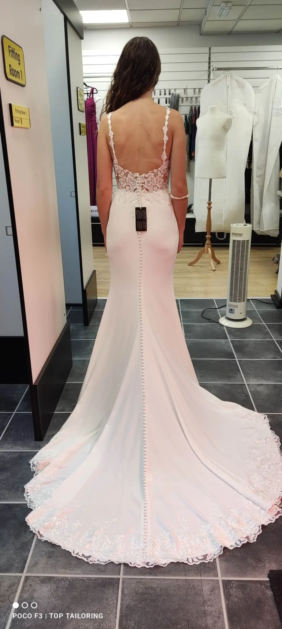 The buttoned back and lace train of a blush bridal gown